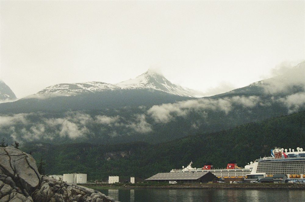 Cruise ship docked in an Alaska harbor beneath cloud-capped mountains