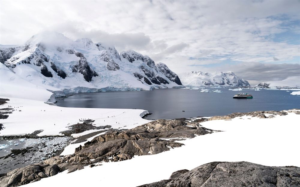 Small ship anchored in a bay ringed by snowy Antarctic peaks