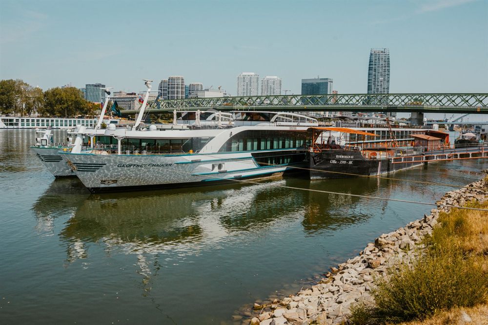 River cruise boats moored along a riverfront below a city skyline